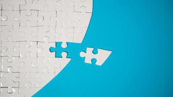 White part of jigsaw puzzle pieces on blue background. concepts of problem solving, business success, teamwork, Team playing jigsaw game incomplete, Texture photo with copy space for text