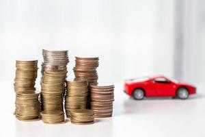 Car toy vehicle with stack coin money on background. Planning to manage transportation finance costs. Concept of car insurance business, saving buy - sale with tax and loan for new car. photo