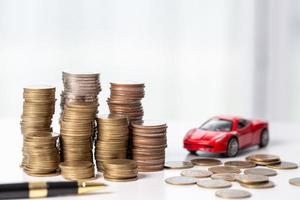 Car toy vehicle with stack coin money on background. Planning to manage transportation finance costs. Concept of car insurance business, saving buy - sale with tax and loan for new car. photo