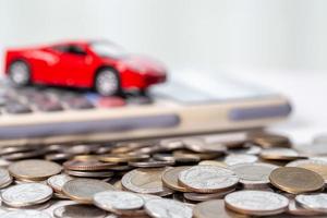 vehículo de juguete de coche con dinero de moneda de pila en el fondo. planificación para administrar los costos de financiación del transporte. concepto de negocio de seguros de automóviles, compra de ahorro - venta con impuestos y préstamo para automóviles nuevos. foto