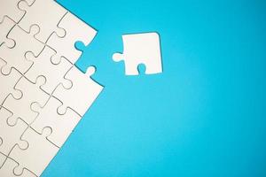 White part of jigsaw puzzle pieces on blue background. concepts of problem solving, business success, teamwork, Team playing jigsaw game incomplete, Texture photo with copy space for text