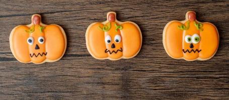 feliz día de halloween con galletas divertidas sobre fondo de mesa de madera. truco o amenaza, hola octubre, otoño otoño, festivo, fiesta y concepto de vacaciones foto