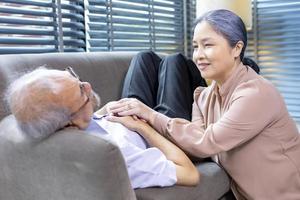 Senior man is suffering from heart attack while his wife is holding his hand for sympathy support and encouragement for compassion and condolence photo