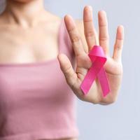 mes de concientización sobre el cáncer de mama de octubre rosa, la mano de la mujer sostiene una cinta rosa y usa una camisa para apoyar la vida y la enfermedad de las personas. concepto del mes nacional de los sobrevivientes del cáncer, la madre y el día mundial del cáncer foto