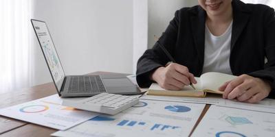 Close-up of business woman hand using a calculator and take notes to check company finances and earnings and budget. photo