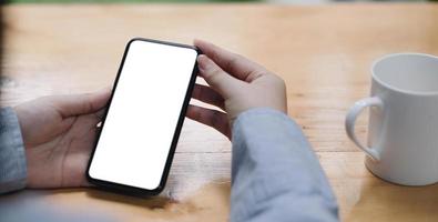 Cropped shot view of woman hands holding smart phone with blank copy space screen for your text message or information content, female reading text message on cell telephone during in urban setting. photo