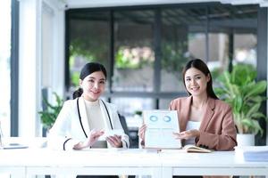 dos mujeres de negocios asiáticas trabajan juntas para hacer el trabajo en la oficina. foto