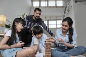 feliz actividad familiar tailandesa encantadora asiática, padres, papá, mamá y niños se divierten jugando y alegres bloques de juguete de madera juntos en el piso de la sala de estar, el fin de semana de ocio y el estilo de vida de bienestar doméstico. foto