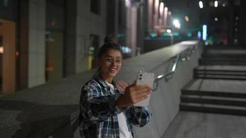 chica usando su teléfono en la ciudad por la noche video