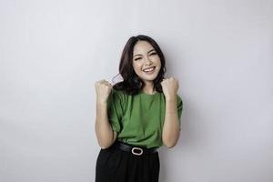 A young Asian woman with a happy successful expression wearing green shirt isolated by white background photo