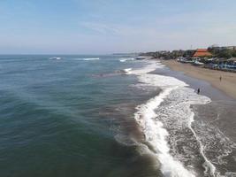 Aerial view of people surfing on waves with surfboards when vacation in Bali, Indonesia photo