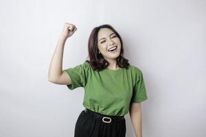 A young Asian woman with a happy successful expression wearing green shirt isolated by white background photo