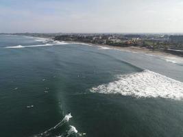 vista aérea de personas surfeando en olas con tablas de surf cuando están de vacaciones en bali, indonesia foto