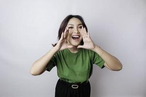 Young beautiful woman wearing a green t-shirt shouting and screaming loud with a hand on her mouth. communication concept. photo