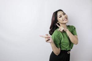 Smiling beautiful Asian woman pointing finger sideward to empty space isolated white background photo