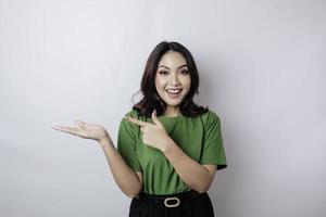 Smiling beautiful Asian woman pointing finger sideward to empty space isolated white background photo