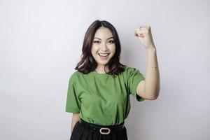 A young Asian woman with a happy successful expression wearing green shirt isolated by white background photo