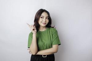 Smiling beautiful Asian woman pointing finger sideward to empty space isolated white background photo