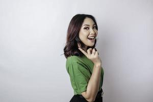 Smiling beautiful Asian woman pointing finger sideward to empty space isolated white background photo