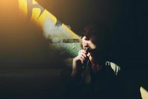 girl sits and smokes electronic cigarette photo