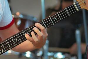 Fingers on strings of an electric bass guitar photo