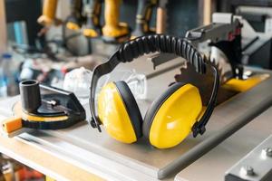 Earmuffs on Electric saw table in workshop .Woodwork safety concept . selective focus photo