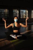 Sporty woman practicing yoga wearing protective mask photo