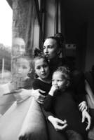 mamá y dos hijas juntas en la ventana foto