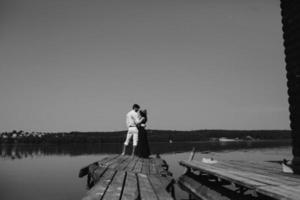 abrazando al hombre y a la mujer enamorados en el muelle de madera foto