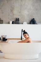 vista lateral de una mujer tomando un baño de espuma en casa foto