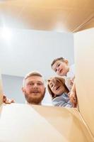 familia feliz recién mudada a una casa nueva y mirando la caja foto