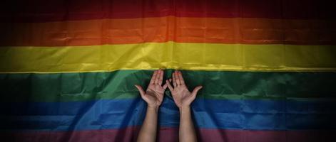 LGBTQ pride flag on black background. Lgbt rainbow flag in gay hand. photo