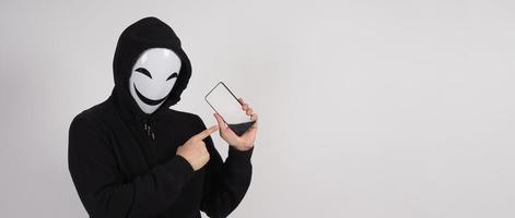 hacker anónimo y mascarilla con smartphone en la mano. foto