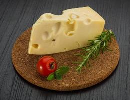 Maasdam cheese on wooden board and wooden background photo