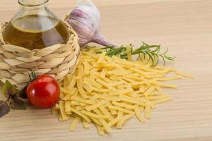 Raw pasta on wooden background photo
