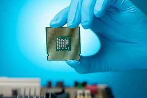 Electronic engineer hand holding computer chip on blue background. Chipset of electronic circuit board for PC motherboard. CPU chip. Electronic components. Computer hardware. Computer processor chip. photo