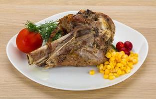 Roasted turkey leg on the plate and wooden background photo