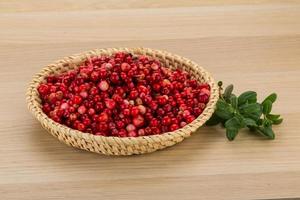 arándano rojo en una cesta sobre fondo de madera foto