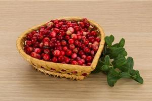 arándano rojo en una cesta sobre fondo de madera foto