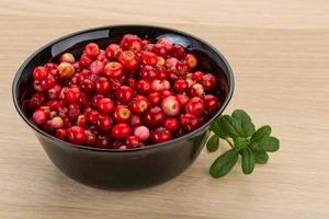 Cowberry in a bowl on wooden background photo