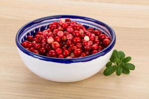 Cowberry in a bowl on wooden background photo