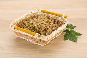 White currant in a basket on wooden background photo