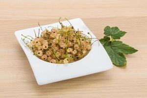 White currant in a bowl on wooden background photo