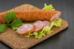 Sausage on wooden board and wooden background photo