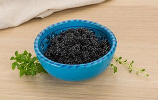 Black caviar in a bowl on wooden background photo