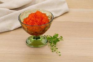 Red caviar in a bowl on wooden background photo