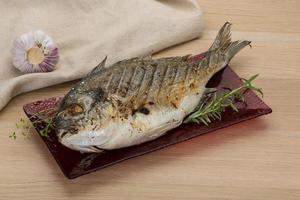 Grilled dorado on the plate and wooden background photo