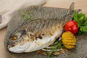 Grilled dorado on the plate and wooden background photo