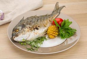 Grilled dorado on the plate and wooden background photo