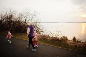 madre con hijas caminando por el sendero junto al lago. foto